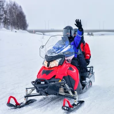 Deux personnes en combinaison d'hiver font une excursion en motoneige lors de leur voyage en Laponie.