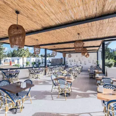 terrasse avec tables en bois et chaises sous une pergola en bambou