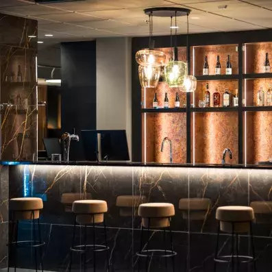 Étagères lumineuses du bar de l'Hôtel Sodankylä présentant une sélection de boissons et spiritueux.