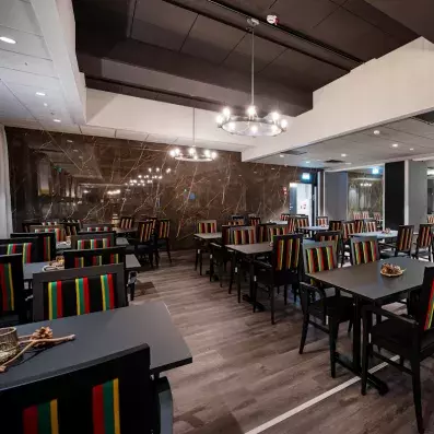 Salle de restaurant spacieuse de l'Hôtel Sodankylä avec chaises colorées et décoration lapone.