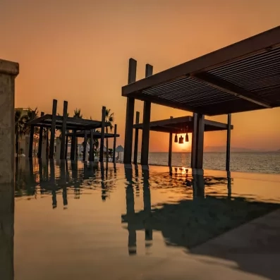 vue sur piscine avec beau coucher de soleil, des cabanes en bois, beach bar