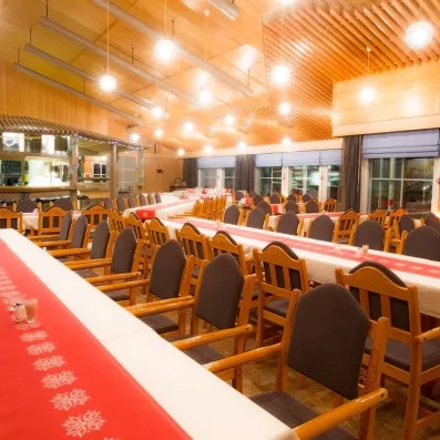 Une grande salle de banquet moderne avec de longues tables et des chaises en bois.