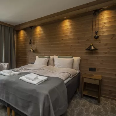 Chambre double élégante avec parement bois et luminaires industriels, confort scandinave à l'Hôtel Matarengi Lodge.