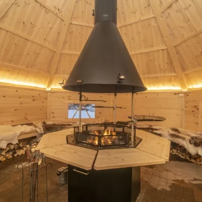 Intérieur d'un kota traditionnel avec feu de camp central, ambiance typique pour des soirées conviviales en famille.