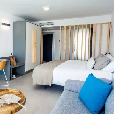 Une vue de la suite montrant un coin salon, un lit et une cloison en bois clair au design original.