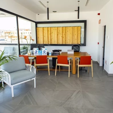 Un espace de réception moderne avec un bureau en bois, des chaises et un fauteuil.