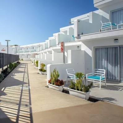 Une allée extérieure desservant des chambres avec de petites terrasses privatives fleuries.