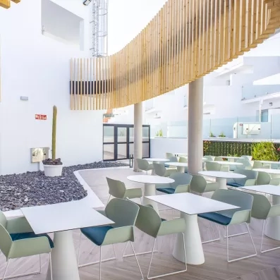 Une terrasse située dans un patio blanc, abritée par une structure décorative en bois.