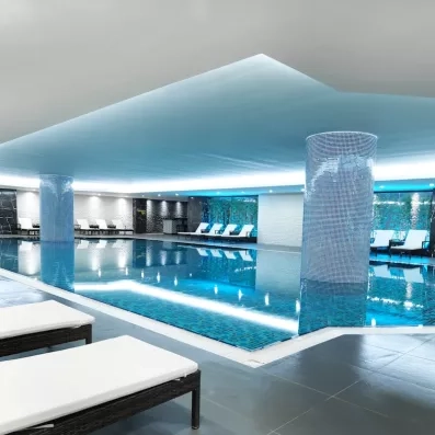 Grande piscine intérieur avec des transats, dans une ambiance relaxante.
