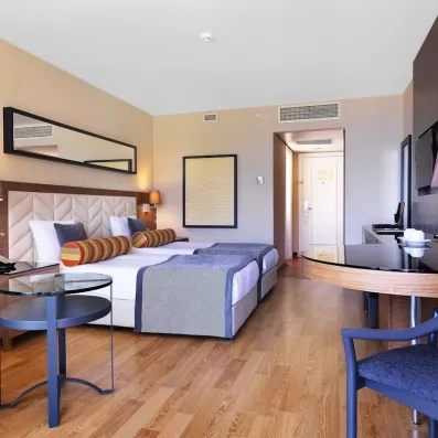 Une chambre avec deux lits simples et un espace bureau avec une table basse et une télévisons.