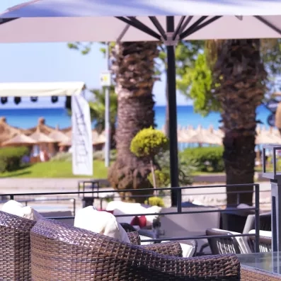 Mobilier de jardin posé sur la terrasse avec des palmiers et vue sur la mer.