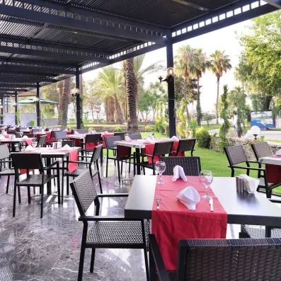 Salle de restauration extérieur sur la terrasse vue sur le jardin de l'hôtel.