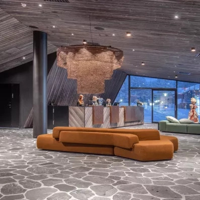 réception moderne de l'hôtel levi spa en laponie finlandaise avec un canapé centrale et un grand lustre et des baies vitrées 