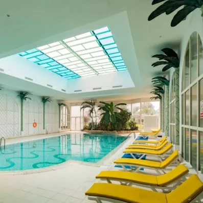 Piscine intérieure avec des transats jaune sur le côté droit 