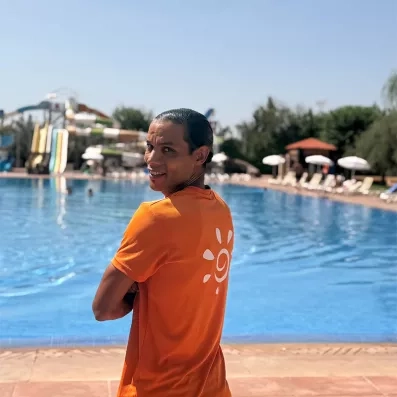 Animateur Mondi Club t shirt orange piscine bleue ciel bleue végétation tobogan