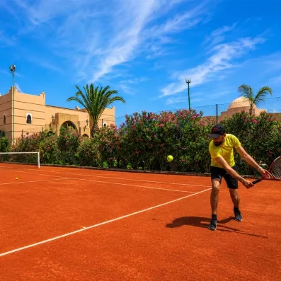 court de tennis en terre battue avec une personne tenant une raquette 