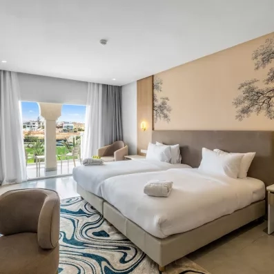 grande chambre grand lit tapis noir et blanc terrasse vue jardin rideaux gris et blanc fauteuil