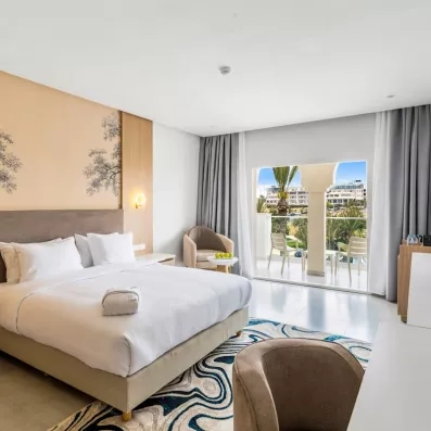 grande chambre grand lit tapis noir et blanc terrasse vue jardin rideaux gris et blanc fauteuils serviette