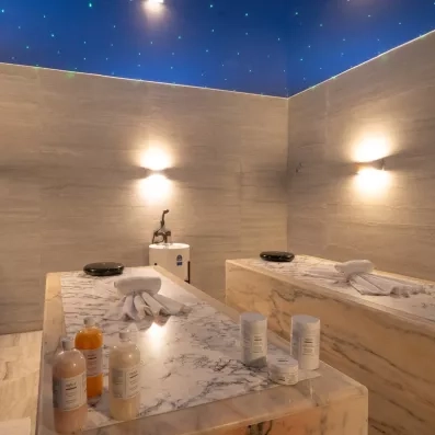 salle de massage special duo serviettes soins bouteilles et pots produits tables effet marbré plafond bleu étoilé