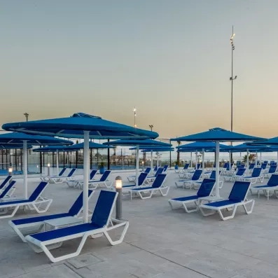 terrasse extérieure parasols et transats bleus et blancs couché de soleil