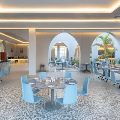 grande salle mosaiques au sol tables chaises grises patio avec palmiers