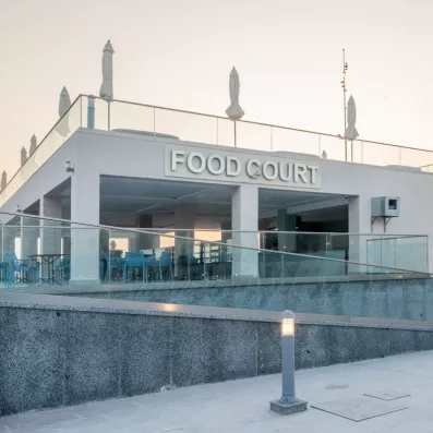 devanture grise food court rampe et terrasse parasols fermés blancs