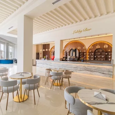 grande salle pour manger chaises tables gris blanc bordures dorées bar marbré et fond alcoves en bois