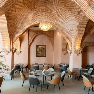 salle a manger style marocain lampe plafond tableau central briques couleur marron clair tables et chaises gris et marron 