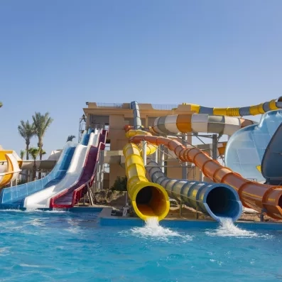 Toboggans aquatiques multicolores à sensations fortes débouchant dans la piscine de l'aquapark d'Hurghada.