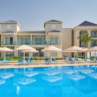 piscine extérieure bleue palmier façade hôtel blanc transat bleu parasols blancs