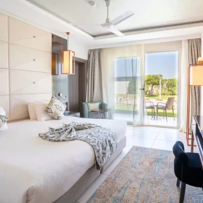 belle grande chambre draps blanc beige pardessus noeud noir blanc marron terrasse ouverte vue sur jardin
