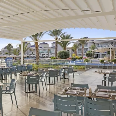 restaurant terrasse couverte extérieure chaises grises palmiers piscine