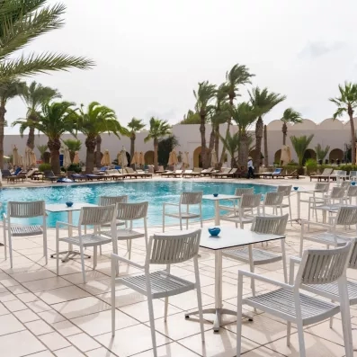 Un espace détente en bord de piscine, entouré de transats et de palmiers, parfait pour profiter du soleil.