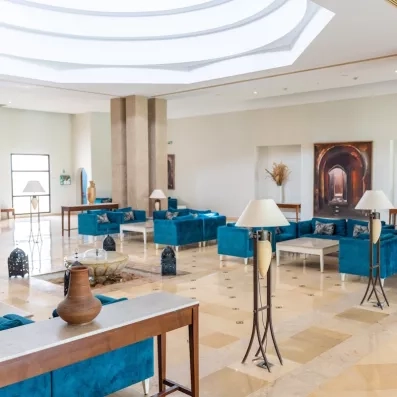 Un lobby spacieux et élégant, aux tons bleu paon et beige, alliant confort et raffinement méditerranéen.