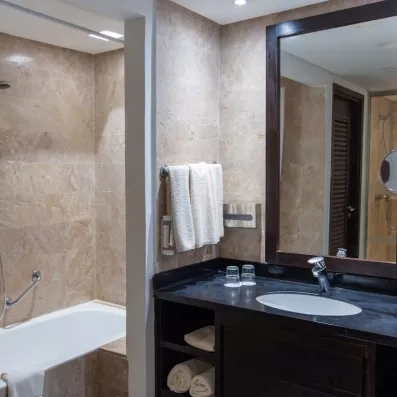 Une salle de bain habillée de marbre beige, équipée d'une baignoire, d'une vasque et d'un grand miroir, pour un moment de détente tout confort.