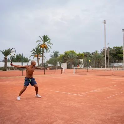 Un court en terre battue entouré de palmiers, pour s'adonner au tennis dans un cadre agréable.