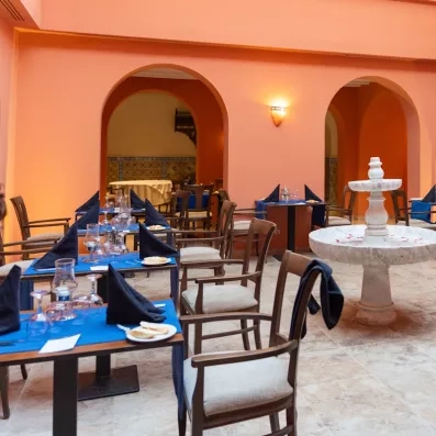 Une salle voûtée aux tons orangés et sa fontaine en marbre, pour un dîner dans un cadre chaleureux et typique.