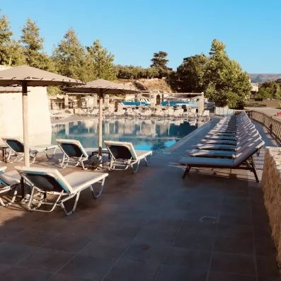 Vue de la terrasses de l'hôtel avec la picsine et des transats.