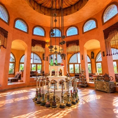 Salle orientale chaleureusement aménagée, dotée de nombreux narguilés, de banquettes décorées