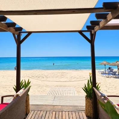 Terrasse ombragée offrant une vue directe sur la plage et la mer