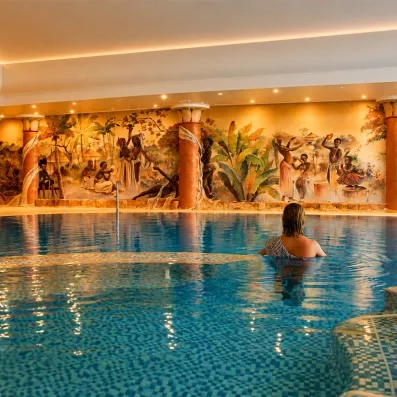 Piscine intérieure décorée de fresques colorées, avec personne profitant de l’eau