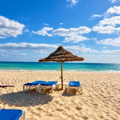 Plage de sable fin avec transats bleus et parasol en chaume