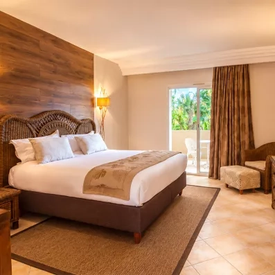 Chambre spacieuse et lumineuse avec grand lit et balcon verdoyant