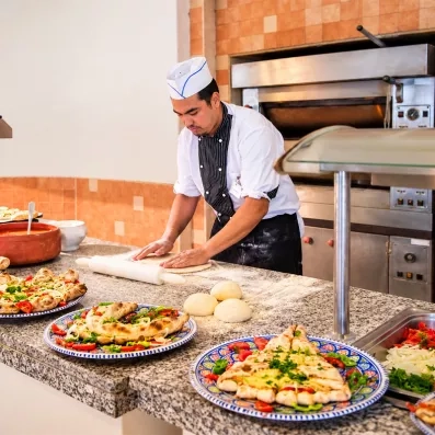 Chef preparant des pizzas fraiches et pains garnis au buffet du Mondi Club Aladin Djerba