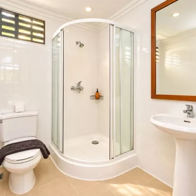 Salle de bain, équipée d'une douche et d'un grand miroir au cadre en bois.