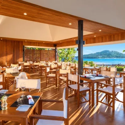 Salle de restaurant en bois, sur la terrasse offrant une vue sur l'océan.