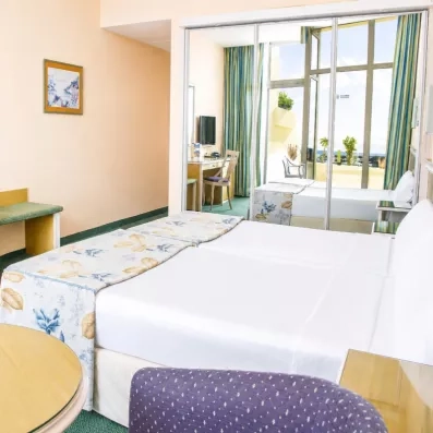 Une vue d'angle d'une chambre montrant le lit et le mobilier en bois clair.