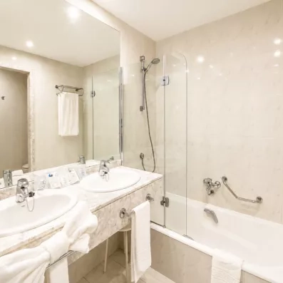Une salle de bain moderne et propre équipée d'une baignoire et d'un grand miroir.