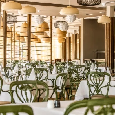Une salle à manger lumineuse avec plusieurs tables et chaises 
