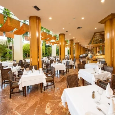 Une salle à manger lumineuse avec plusieurs tables et chaises 